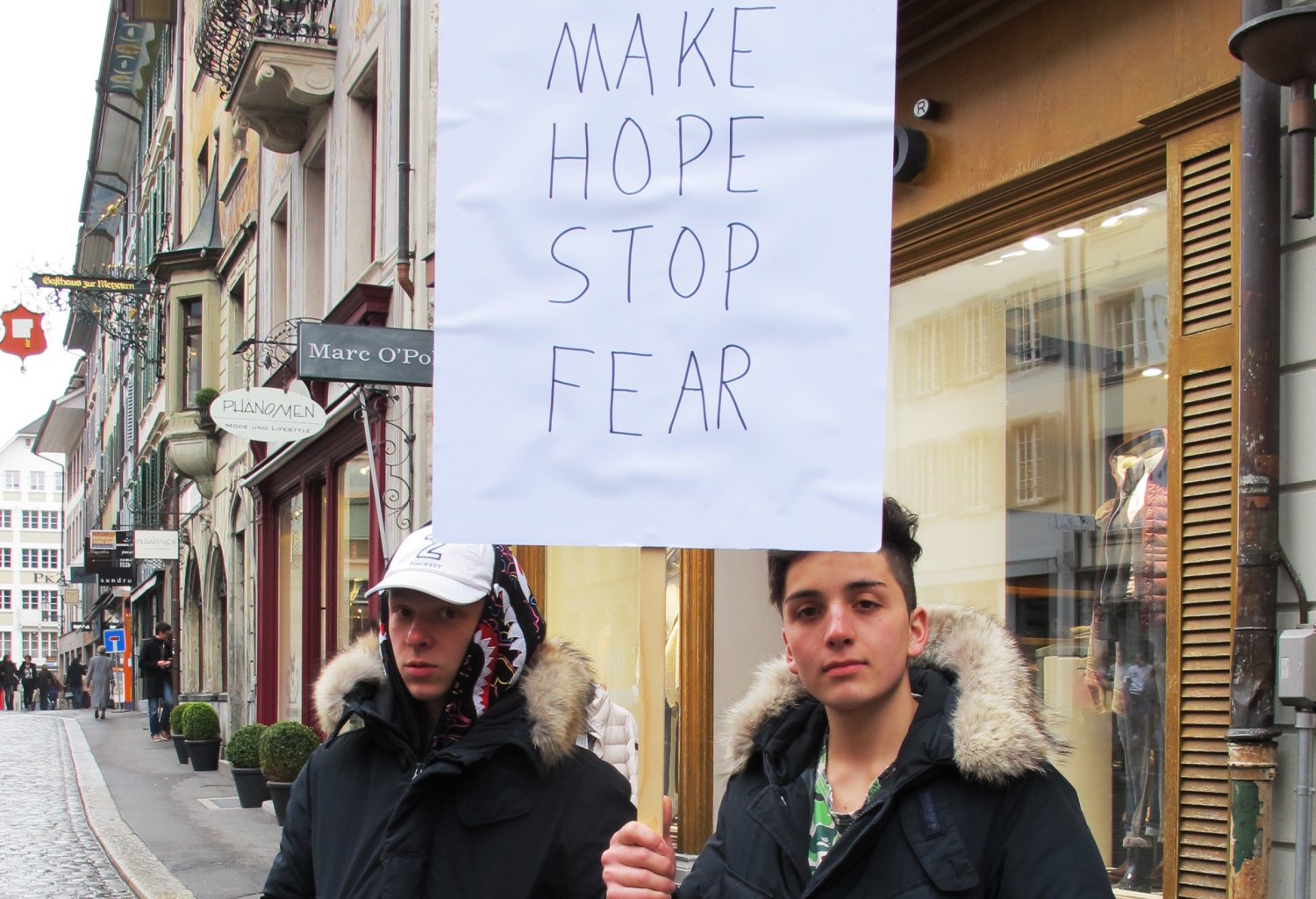 Two boys hold up a sign saying "Make Hope Stop Fear"